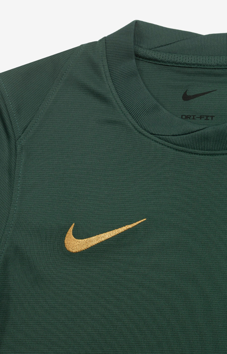 Pormenor do swoosh Nike dourado da Camisola 120 Anos Strike 26/27 de Criança do Sporting.