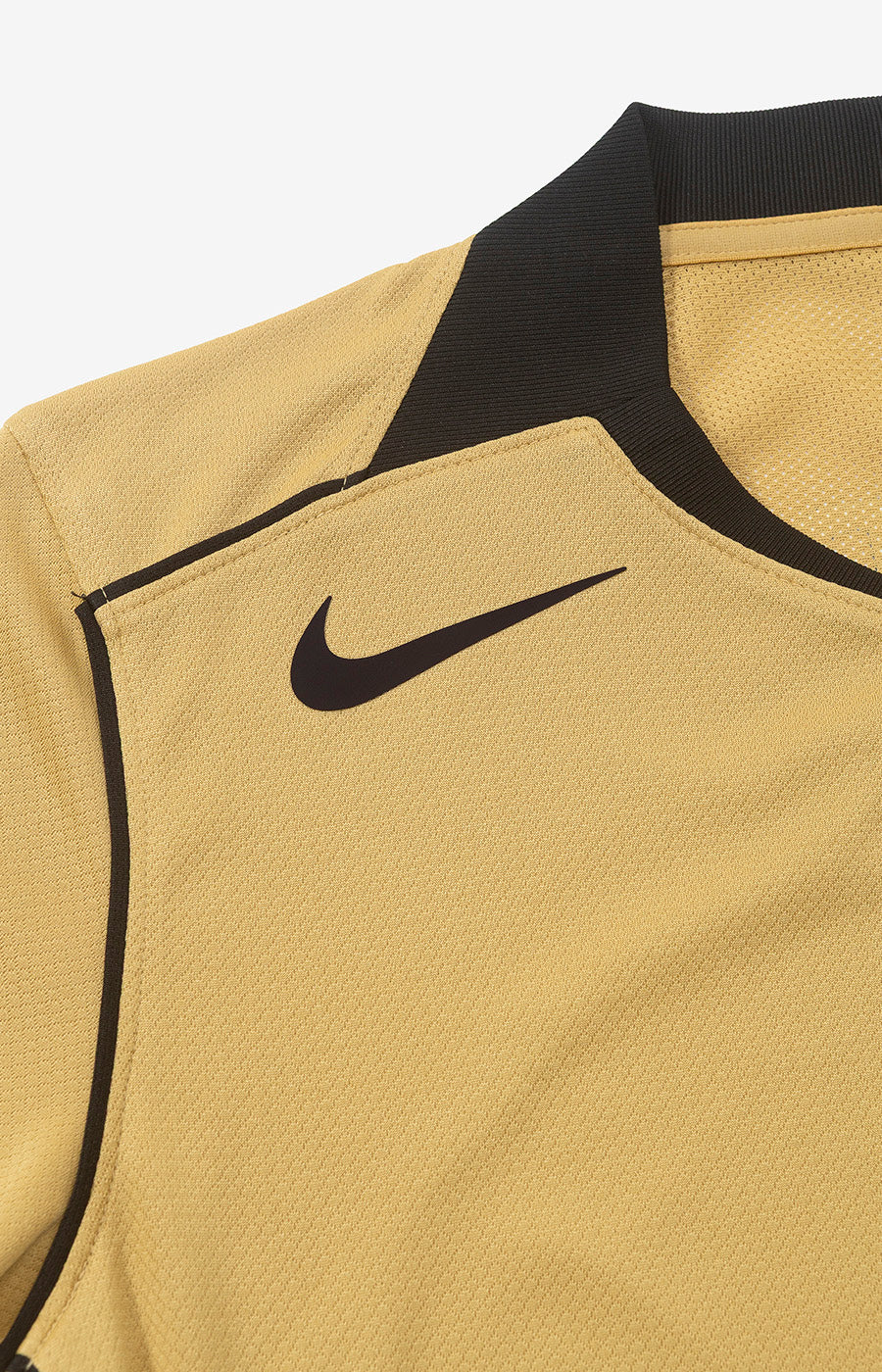 Le logo Nike « Swoosh » noir sur le haut de la poitrine du maillot alternatif « Total 90 » doré du Sporting pour la saison 26/27.