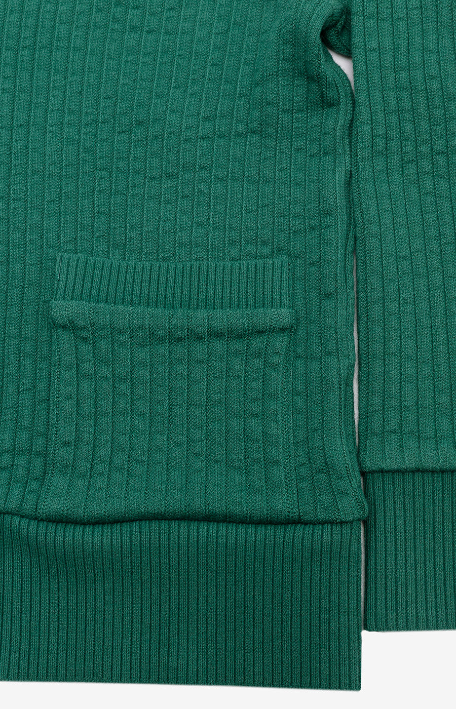 Detalhe do bolso frontal e do acabamento canelado do Cardigan Jubas verde para criança.