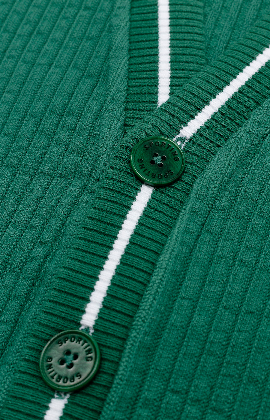 Detalhe dos botões e do acabamento branco frontal do Cardigan Jubas verde para criança.