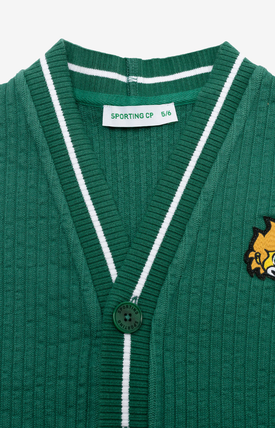 Detalhe da gola em V e dos acabamentos brancos do Cardigan Jubas verde para criança.