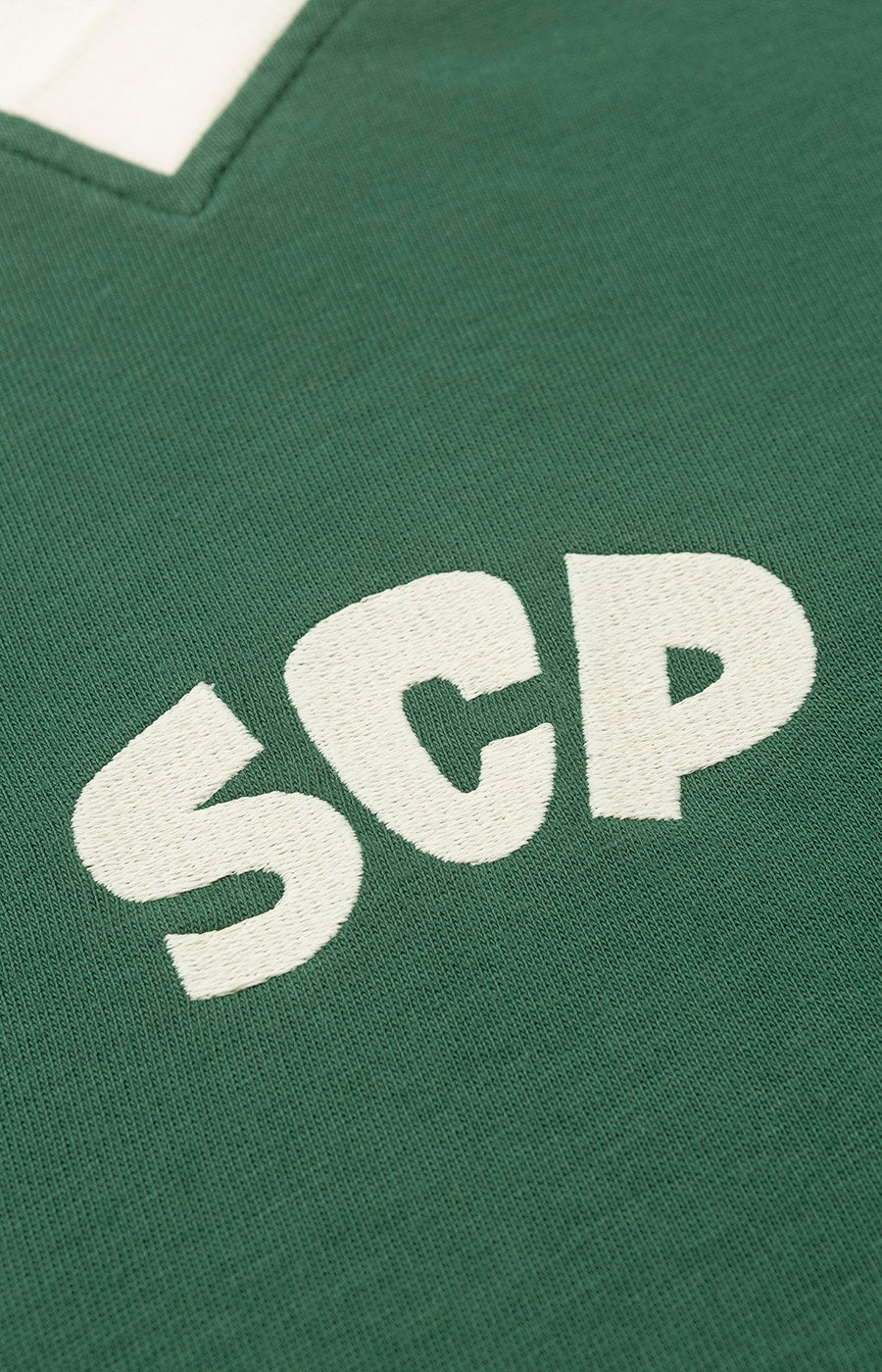 Pormenor das letras SCP aplicadas ao peito do Polo Manga Comprida Verde Escuro do Sporting.