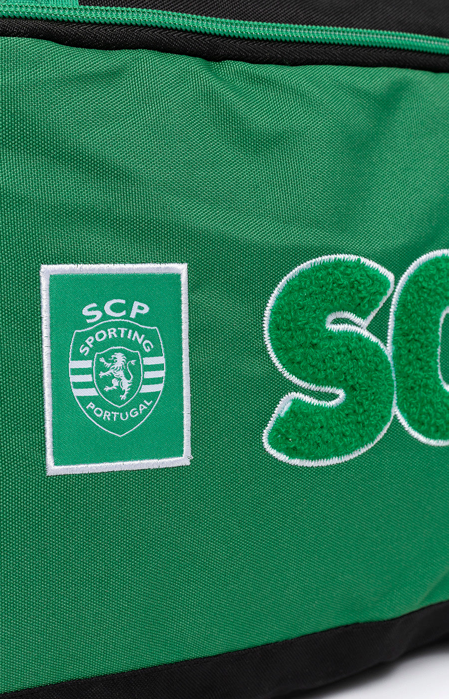 Emblema e letras SCP aplicados na frente do Saco de Desporto Escolar do Sporting.