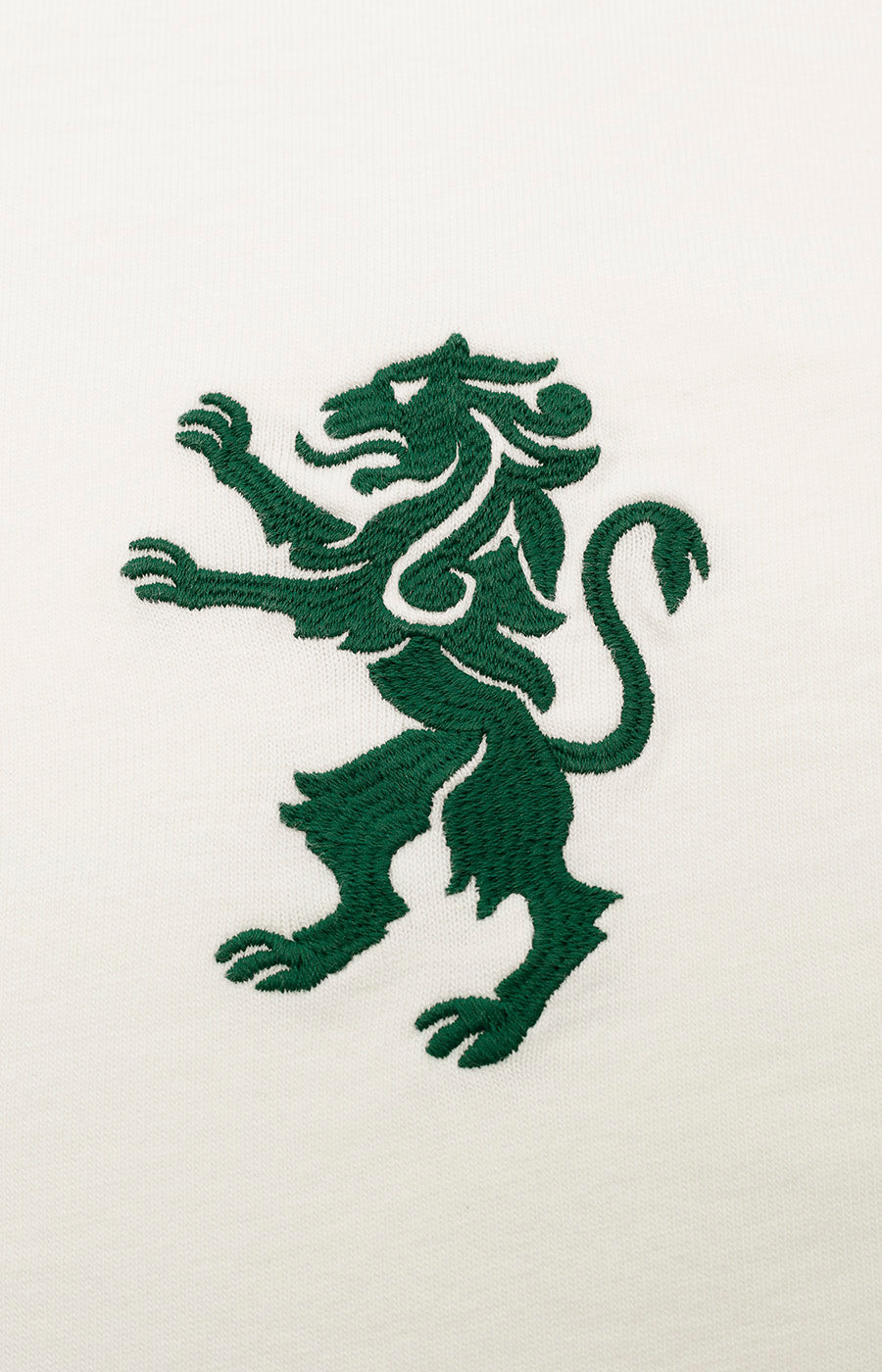 Leão verde bordado ao peito da T-shirt Branca Leão Sporting, visto de perto.