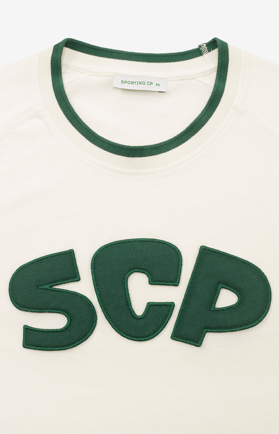 Pormenor das iniciais SCP bordadas em verde no peito da T-shirt Branca Retro do Sporting.